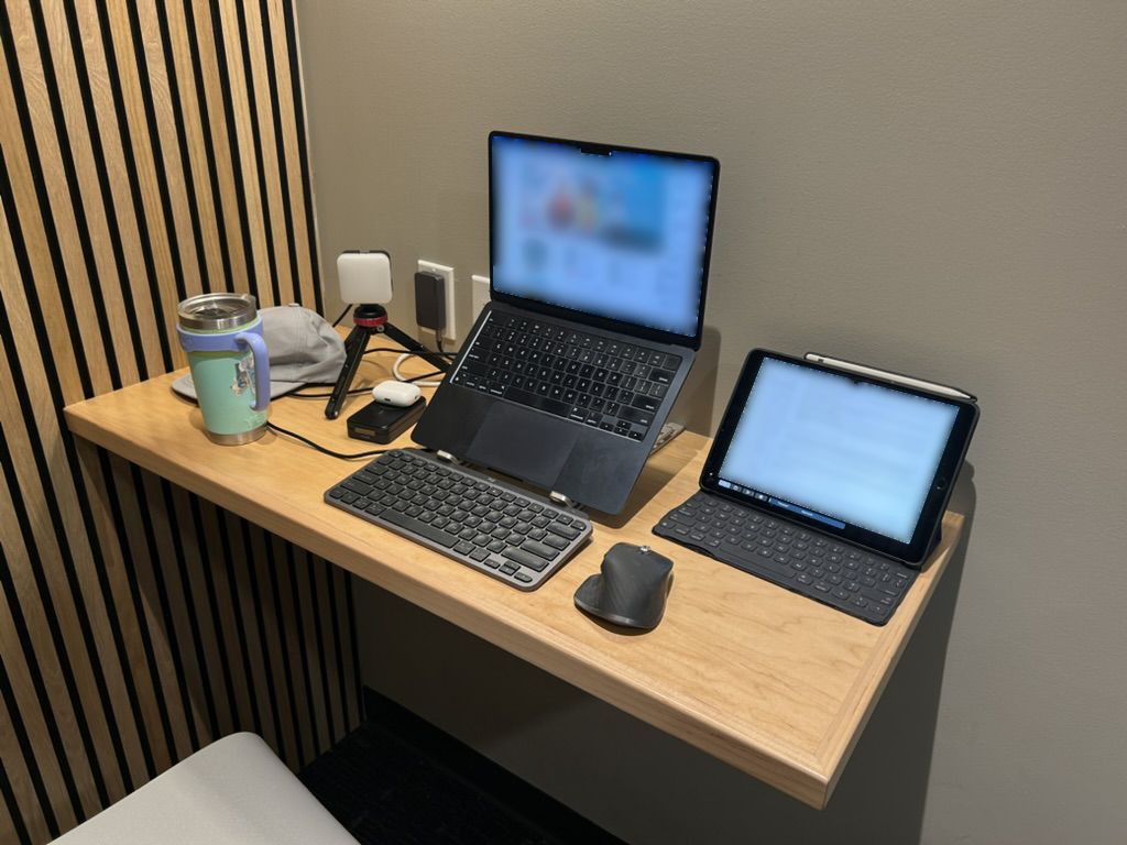 Typical mobile workstation setup — laptop, second screen, cables, and loose gear spread across a desk